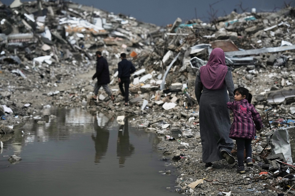 Palestinians walk through the rubble amid stormy weather in Gaza City Thursday, Dec. 11, 2025. (AP Photo/Jehad Alshrafi)