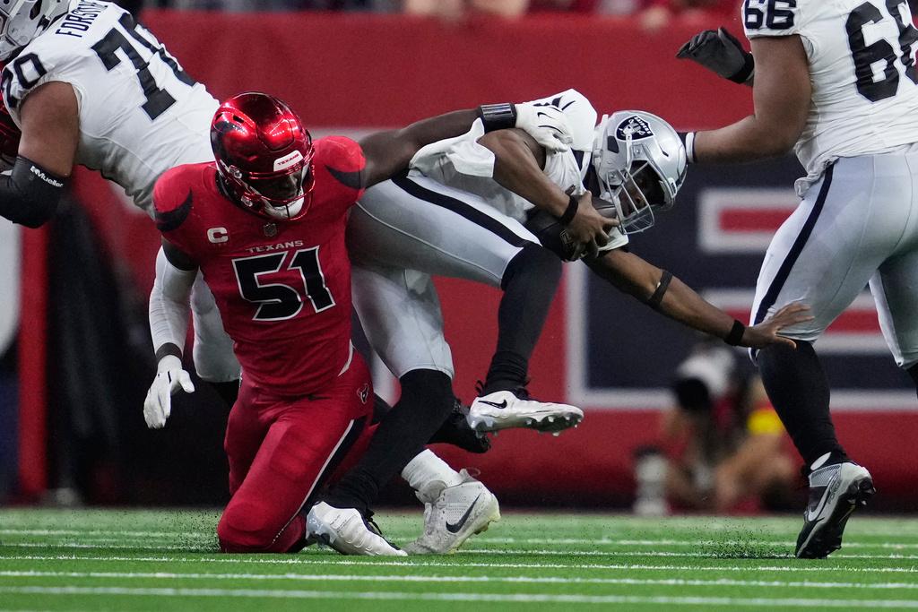 Las Vegas Raiders quarterback Geno Smith, right, scrambles away from Houston Texans defensive end Will Anderson Jr. (51) during the second half of an NFL football game, Sunday, Dec. 21, 2025, in Houston. (AP Photo/Ashley Landis)