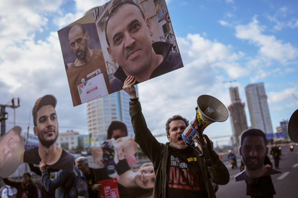 FILE - A demonstrator wave photos of freed Israeli hostage Eli Sharabi before and after his captivity blocks a highway during a protest demanding all hostages release from Hamas captivity, in Tel Aviv, Israel, Thursday, Feb. 13, 2025. (AP Photo/Oded Balilty, File)