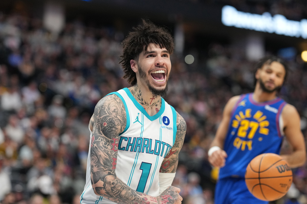 Charlotte Hornets guard LaMelo Ball reacts after dunking the ball for a basket as Denver Nuggets guard Jamal Murray looks on in the second half of an NBA basketball game Sunday, Jan. 18, 2026, in Denver. (AP Photo/David Zalubowski)