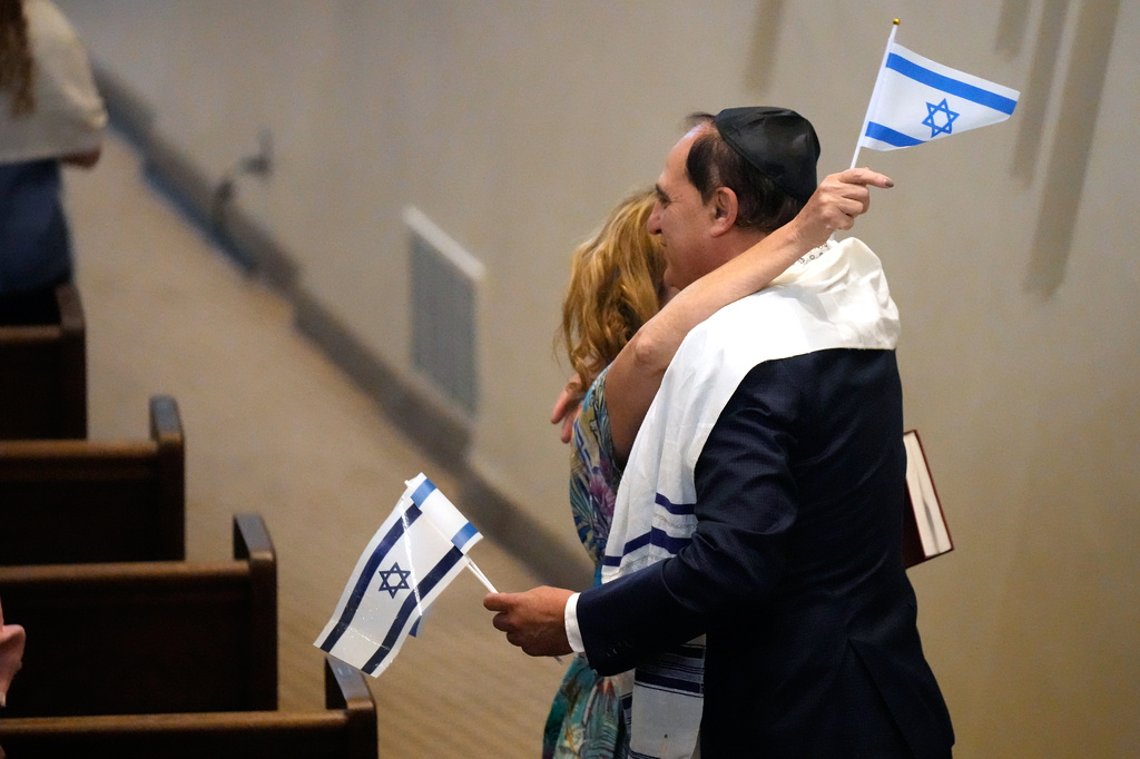 FILE - People hold Israeli flags as they hug during Shabbat Services at The Sinai Temple in Los Angeles, Oct. 14, 2023. (AP Photo/Damian Dovarganes, File)