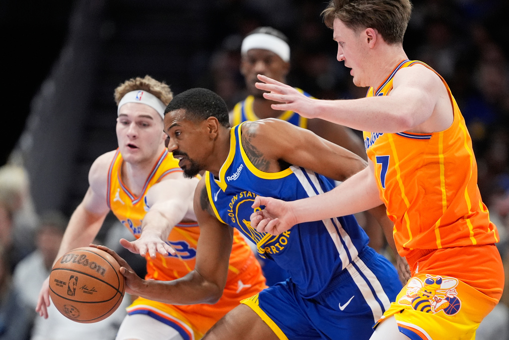Golden State Warriors guard De'Anthony Melton drives to the basket between Charlotte Hornets guard Liam McNeeley and guard Kon Knueppel during the first half of an NBA basketball game, Wednesday, Dec. 31, 2025, in Charlotte, N.C. (AP Photo/Chris Carlson)