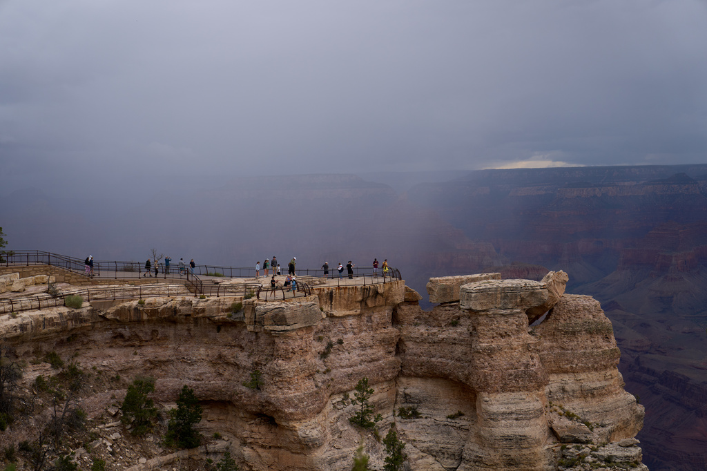 People stand at the rim of the Grand Canyon as rain moves into the canyon, Monday, Aug. 31, 2026, in Grand Canyon National Park, Ariz. (AP Photo/John Locher)