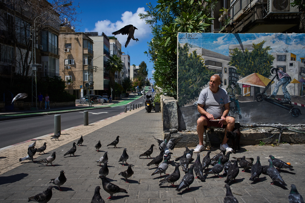 A man feeds birds on a street in Tel Aviv, Israel, after the announcement of a two-week ceasefire with Iran, Wednesday, April 8, 2026. (AP Photo/Oded Balilty)