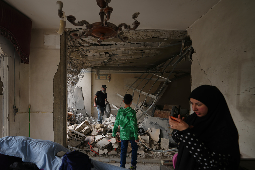 Fadi Al Zein, left, who lost both his homes in Israeli strikes in his village of Khiam and in Dahiyeh, searches through the rubble of his heavily damaged home as a child stands nearby, in Beirut's southern suburbs, Lebanon, Saturday, April 25, 2026. (AP Photo/Hassan Ammar)