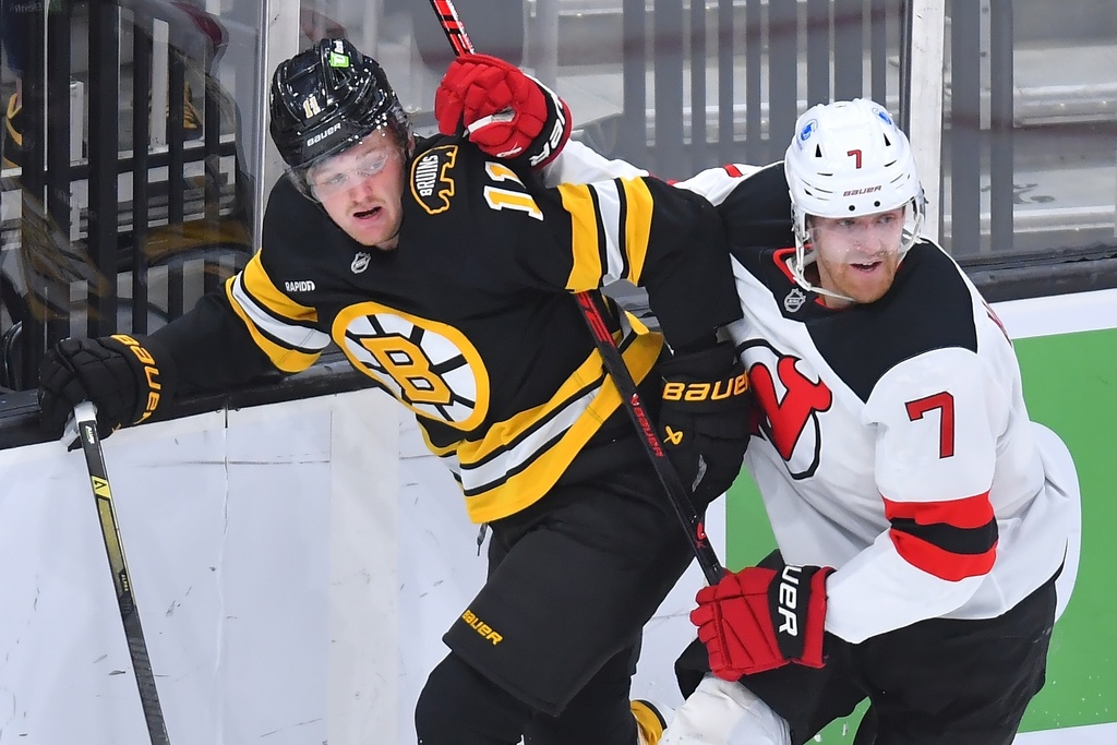 Boston Bruins center Casey Mittelstadt (11) and New Jersey Devils defenseman Dougie Hamilton (7) crash into the boards in the first period of an NHL hockey game, Saturday, Dec. 6, 2025, in Boston. (AP Photo/Steven Senne)