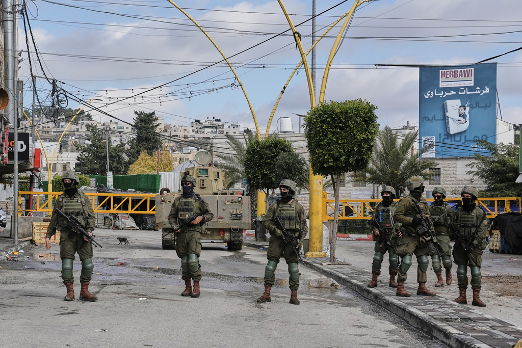 Israeli soldiers take up positions during an army raid in the West Bank city of Hebron Monday, Jan. 19, 2026. (AP Photo/Mahmoud Illean)