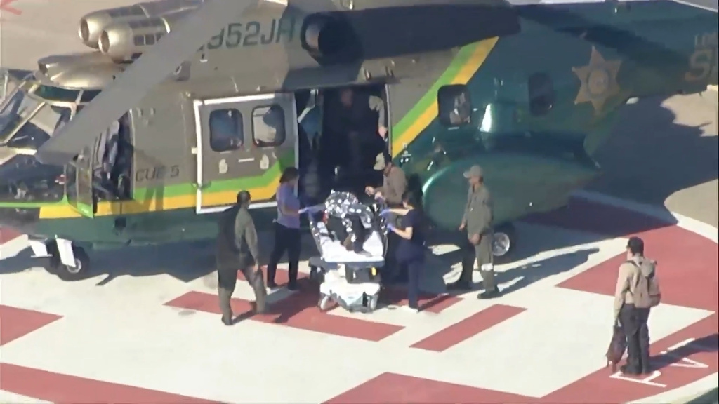 Individuals are stretchered off after a police helicopter lands on helipad on Monday, Dec. 30, 2025 in San Bernardino, Calif. (ABC7 Los Angeles via AP)