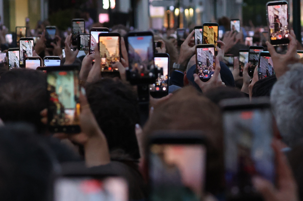 Members of the crowd take pictures and video on their phones as they watch U2 perform an impromptu concert from a balcony in central Dublin, Ireland, Friday, Sept. 25, 2026. (AP Photo/Peter Morrison)
