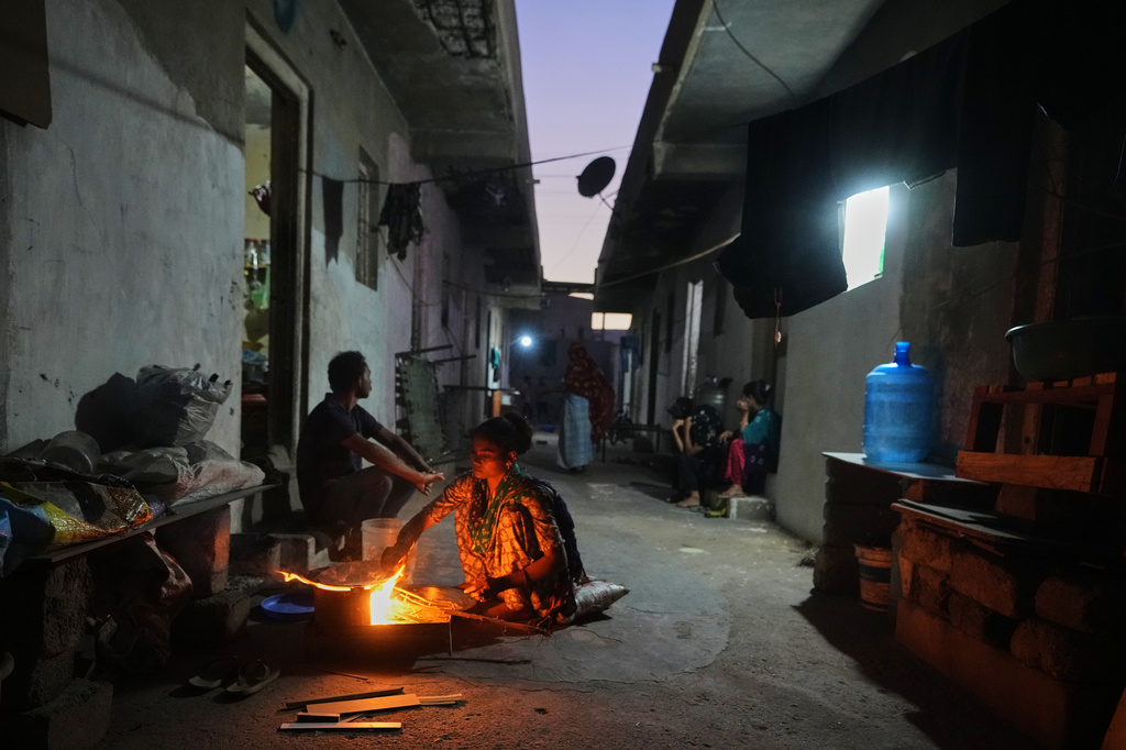 A migrant woman prepares a meal using firewood at a deserted ceramics workers' quarters in Morbi, in the Indian state of Gujarat, Wednesday, April 8, 2026. (AP Photo/Ajit Solanki)