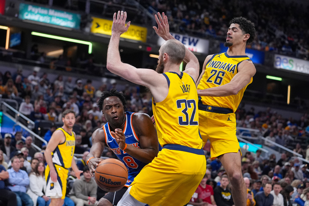 New York Knicks guard OG Anunoby (8) makes a pass around Indiana Pacers center Jay Huff (32) during the first half of an NBA basketball game in Indianapolis, Friday, March 13, 2026. (AP Photo/Michael Conroy)