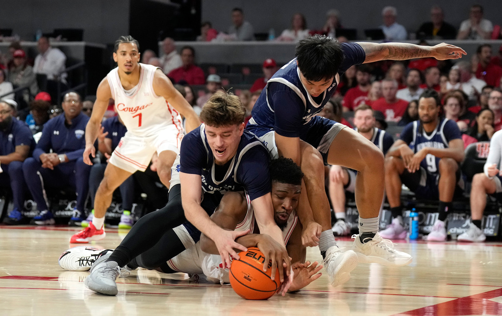 New Orleans forward Enzo Boudouma, left, battles for a loose ball against Houston center Cedric Lath, center, and New Orleans guard Irish Coquia, right, during the first half of an NCAA college basketball game, Saturday, Dec. 13, 2025, in Houston. (AP Photo/Karen Warren)