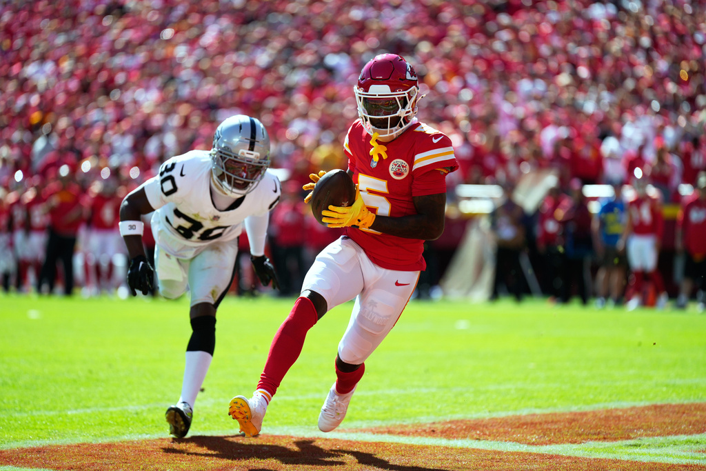 Kansas City Chiefs wide receiver Hollywood Brown (5) scores as Las Vegas Raiders cornerback Darnay Holmes (30) defends during the first half of an NFL football game Sunday, Oct. 19, 2025, in Kansas City, Mo. (AP Photo/Charlie Riedel)