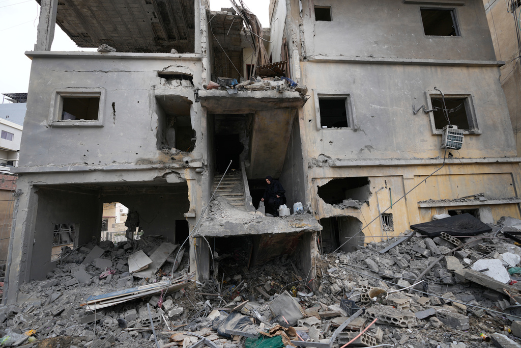 A woman takes the stairs on a destroyed building that was hit in an Israeli airstrike in the southern port city of Tyre, Lebanon, Thursday, March 26, 2026. (AP Photo/Hussein Malla)