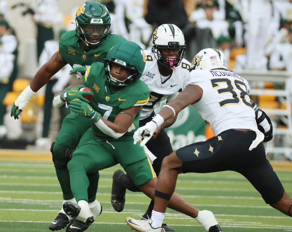 Baylor running back Bryson Washington is pressured by UCF linebacker Jayden McDonald for a short gain during the first half of an NCAA college football game, Saturday, Nov. 1, 2025, in Waco, Texas. (Rod Aydelotte/Waco Tribune-Herald via AP)
