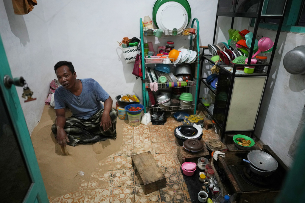 Sahnawi sits on sand in the kitchen of his house in Legung Timur village in Sumenep on Madura Island, Indonesia, Tuesday, Sept. 9, 2025. (AP Photo/Dita Alangkara)