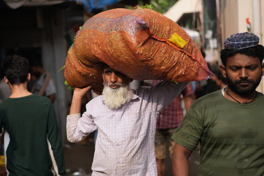 A vegetable vendor carries a sack of vegetables at a local market in Mumbai, India, Sunday, Feb. 1, 2026. (AP Photo/Rafiq Maqbool)