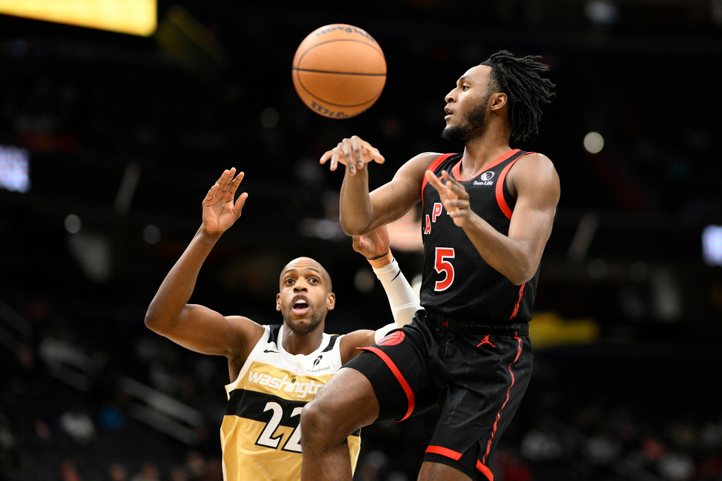Toronto Raptors guard Immanuel Quickley (5) passes the ball against Washington Wizards forward Khris Middleton (22) during the first half of an NBA basketball game, Friday, Dec. 26, 2025, in Washington. (AP Photo/Nick Wass)
