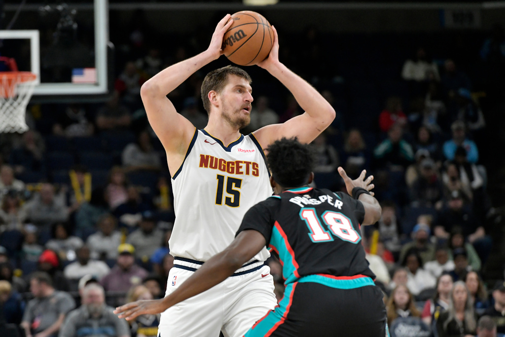 Denver Nuggets center Nikola Jokic (15) handles the ball against Memphis Grizzlies forward Olivier-Maxence Prosper (18) in the first half of an NBA basketball game Wednesday, March 18, 2026, in Memphis, Tenn. (AP Photo/Brandon Dill)