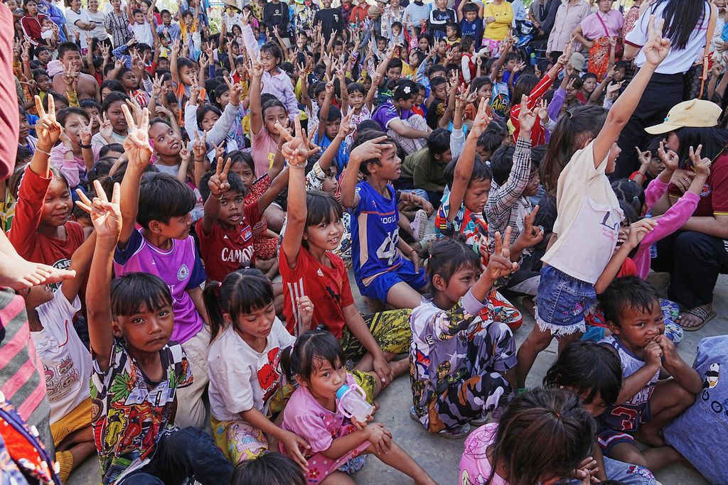 Children raise their hands while receiving donation from charity as they take refuge in Banteay Menchey provincial town, Cambodia, Saturday, Dec. 13, 2025, after fleeing homes following fighting between Thailand and Cambodia. (AP Photo/Heng Sinith)