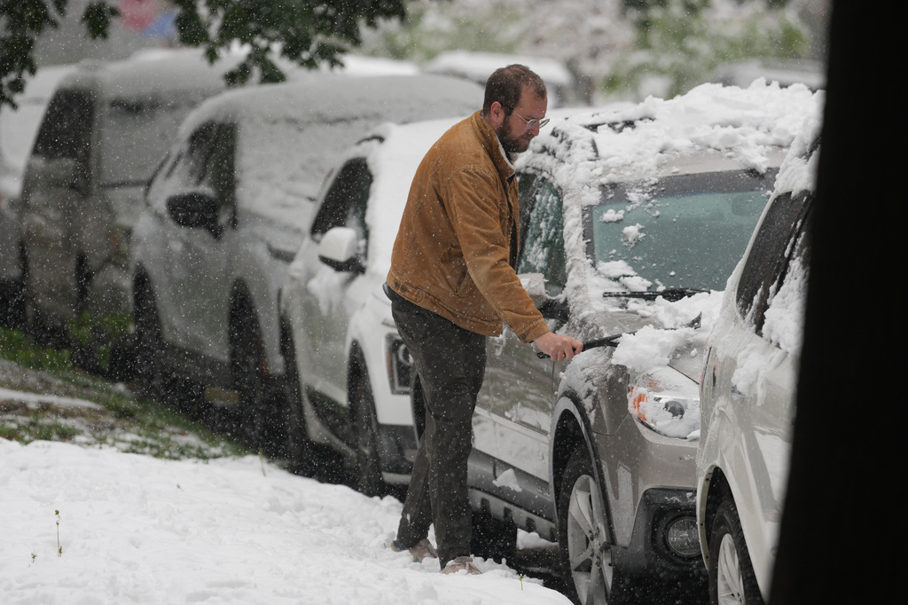 A motorist clears snow from a utility vehicle as a spring storm packing cold temperatures and snow sweeps over the intermountain West, Wednesday, May 6, 2026, in Denver. (AP Photo/David Zalubowski)