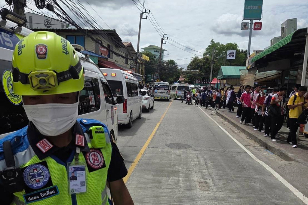 Schoolchildren walk on a road outside a school where deaths and injuries were reported after a shooting in Thailand's Nonthaburi province, Friday, Aug. 7, 2026. (Por Tek Tueng Nonthaburi via AP)