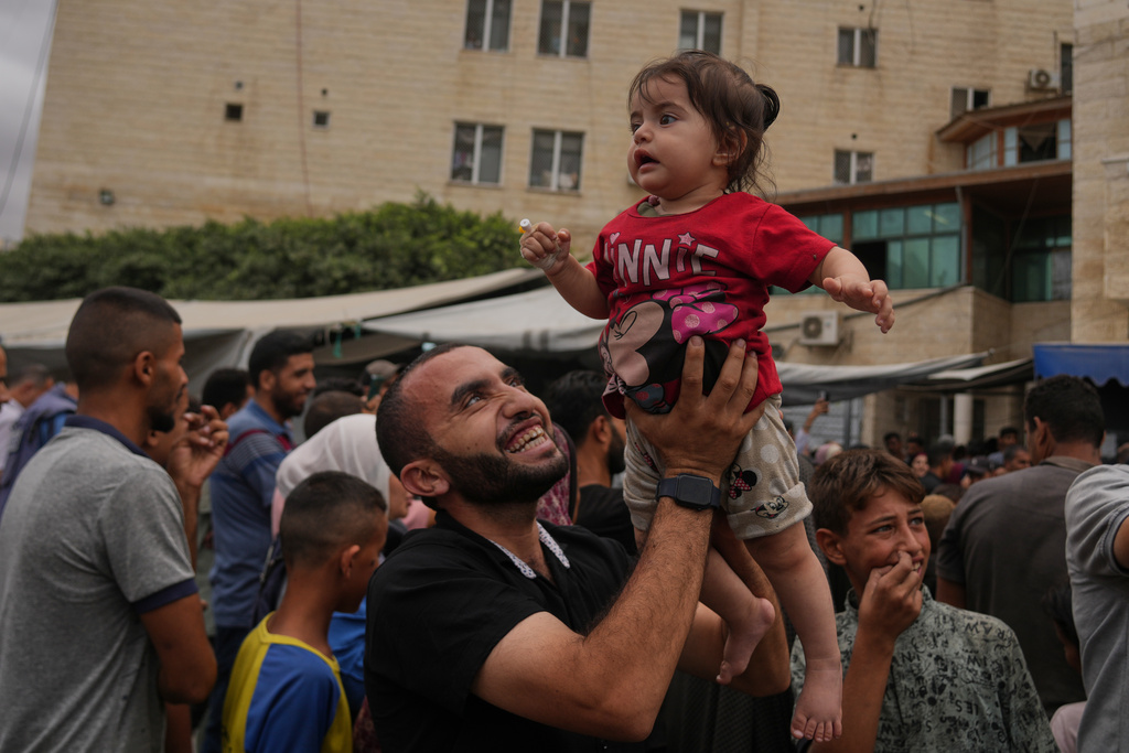 Palestinians celebrate following the announcement that Israel and Hamas have agreed to the first phase of a peace plan to pause the fighting, outside Al-Aqsa Hospital in Deir al-Balah, central Gaza Strip, Thursday, Oct. 9, 2025. (AP Photo/Abdel Kareem Hana)