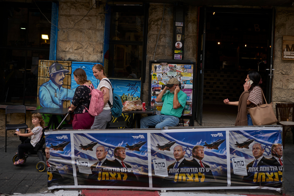 People walk next to a Likud party campaign ad featuring Israeli Prime Minister Benjamin Netanyahu and U.S. President Donald Trump, with a Hebrew message reading "We have one opportunity to win," in Jerusalem on Wednesday, Oct. 28, 2026, a day after the elections in Israel. (AP Photo/Ohad Zwigenberg)