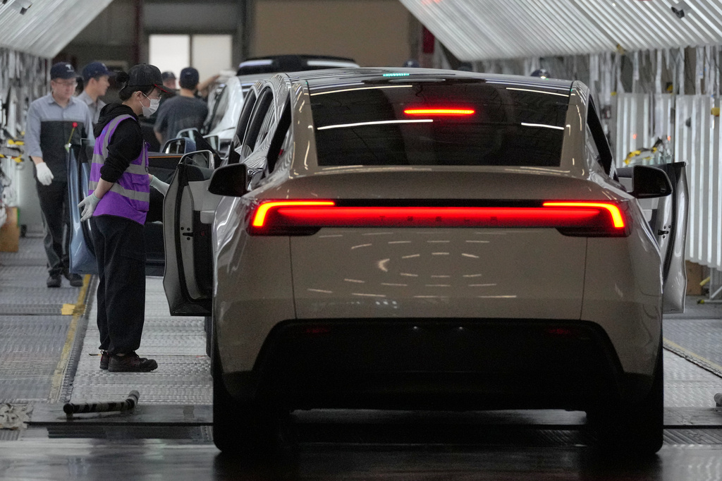 Workers check on a Tesla Model Y at the Tesla Gigafactory assembly plant during a media organized tour, in Shanghai, China, Tuesday, April 14, 2026. (AP Photo/Andy Wong)