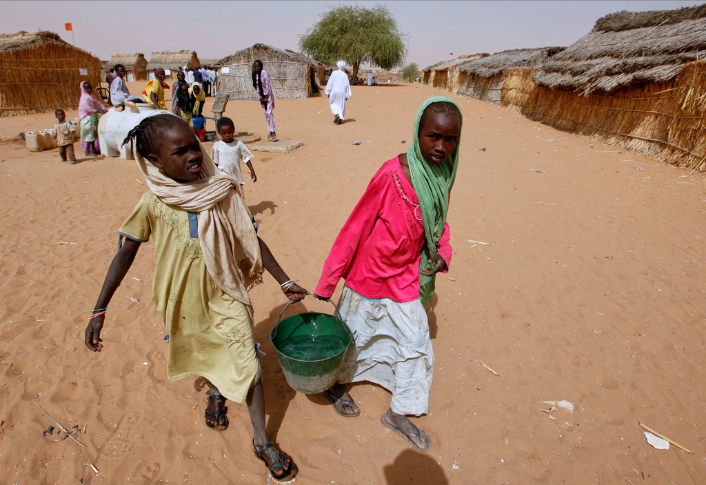 FILE - Sudanese refugee girls carry water supplies near a polling station in the refugee camp of Zamzam, on the outskirts of El Fasher, Darfur, Sudan, on April 13, 2010. (AP Photo/Nasser Nasser, File)