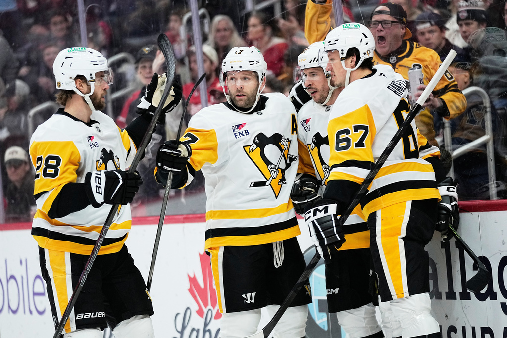 Pittsburgh Penguins right wing Bryan Rust, second from left, celebrates with defenseman Parker Wotherspoon, center Sidney Crosby, and right wing Rickard Rakell, from left, after scoring during the first period of an NHL hockey game against the Detroit Red Wings Saturday, Jan. 3, 2026, in Detroit. (AP Photo/Ryan Sun)