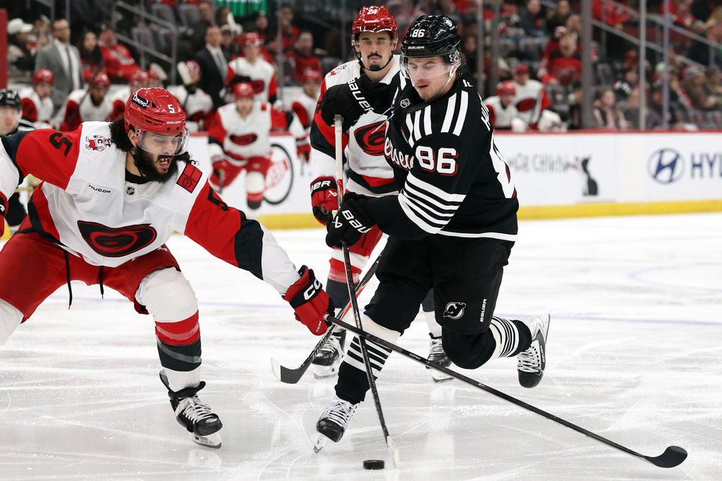 New Jersey Devils center Jack Hughes (86) has his shot knocked away by Carolina Hurricanes defenseman Jalen Chatfield (5) during the second period of an NHL hockey game Saturday, Jan. 17, 2026, in Newark, N.J. (AP Photo/Adam Hunger)