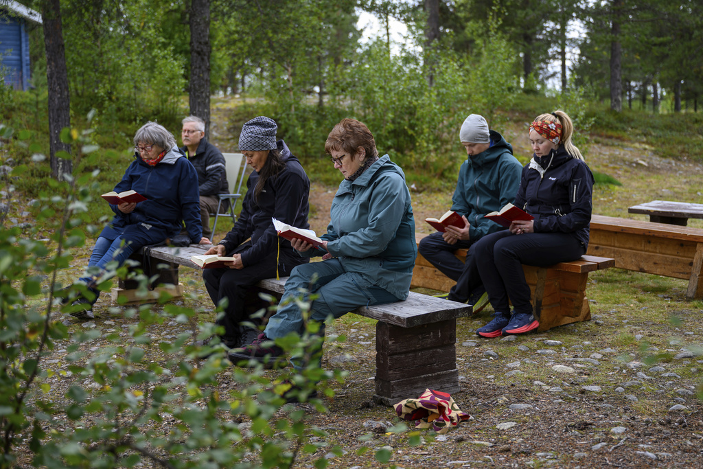 People hold an outdoor prayer for the move of the Kiruna Church, a Sami style wooden Swedish Lutheran church, called Kiruna Kyrka in Swedish, in Kiruna, Sweden, Sunday, Aug. 17, 2025, two days before its move along a 5-kilometer (3-mile) route east to a new city center as part of the town's relocation. (AP Photo/Malin Haarala)