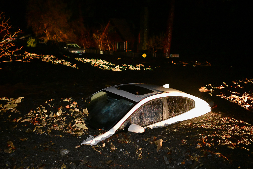 A car sits buried in mud after flooding Wednesday, Dec. 24, 2025, in Wrightwood, Calif. (AP Photo/Wally Skalij)