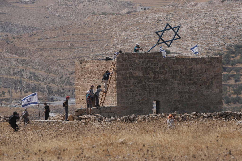 Israeli and foreign peace activists take down a metal structure in the shape of a Star of David from atop a Palestinian structure during a protest in support of local landowners whose property is threatened with seizure by Israeli settlers, on the outskirts of the West Bank city of Beit Sahour, Friday, Aug. 14, 2026. (AP Photo/Mahmoud Illean)