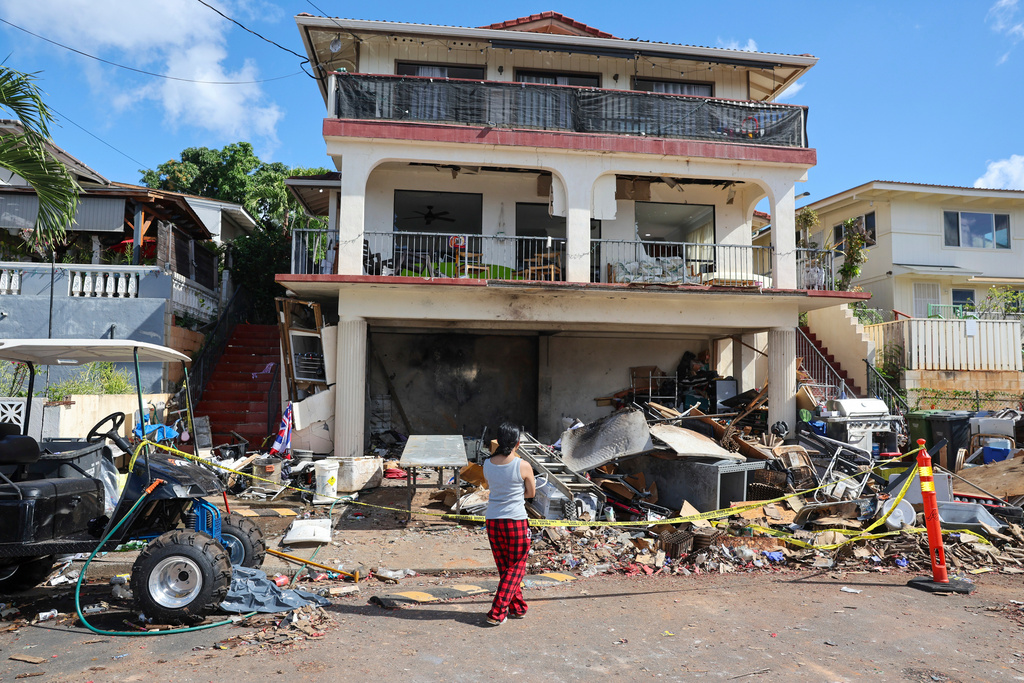 FILE - A woman stands in front of the home where a New Year's Eve firework explosion killed and injured people, Jan. 1, 2025, in Honolulu. (AP Photo/Marco Garcia, File)