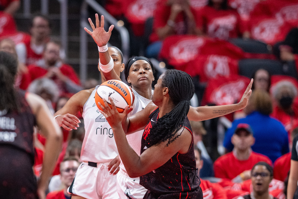 Las Vegas Aces forward NaLyssa Smith, back right, reaches out to block a shot-attempt by Indiana Fever guard Shey Peddy, front right, during the first half of Game 4 of a WNBA basketball playoff semifinals series in Indianapolis, Sunday, Sept. 28, 2025. (AP Photo/Doug McSchooler)