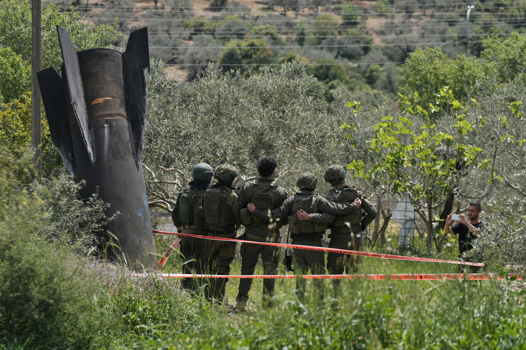 Israeli soldiers take their photo beside the wreckage of an Iranian missile that landed in the West Bank village of Kifl Haris Tuesday, March 24, 2026. (AP Photo/Majdi Mohammed)