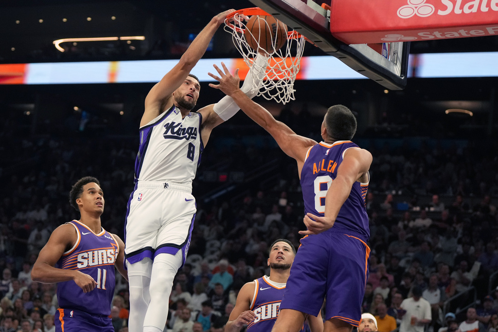 Sacramento Kings guard Zach LaVine (8) dunks over Phoenix Suns forward Oso Ighodaro (11), guard Devin Booker, and guard Grayson Allen (8) during the first half of an NBA basketball game, Wednesday, Oct. 22, 2025, in Phoenix. (AP Photo/Rick Scuteri)