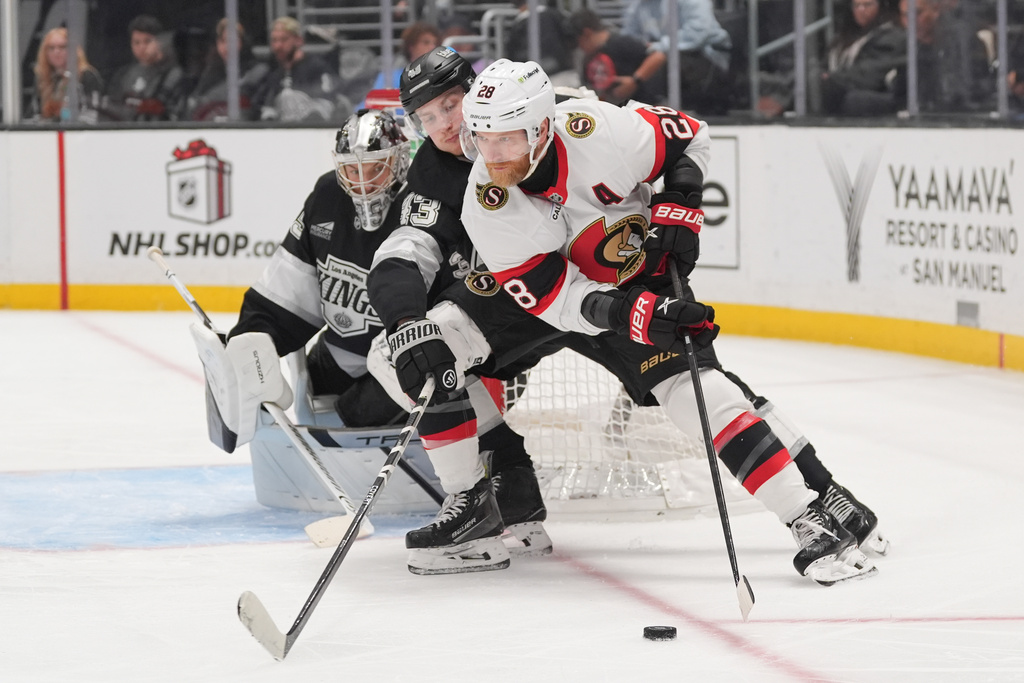 Ottawa Senators right wing Claude Giroux (28) moves the puck under defense by Los Angeles Kings defenseman Jacob Moverare (43) during the third period of an NHL hockey game Monday, Nov. 24, 2025, in Los Angeles. (AP Photo/Jae C. Hong)