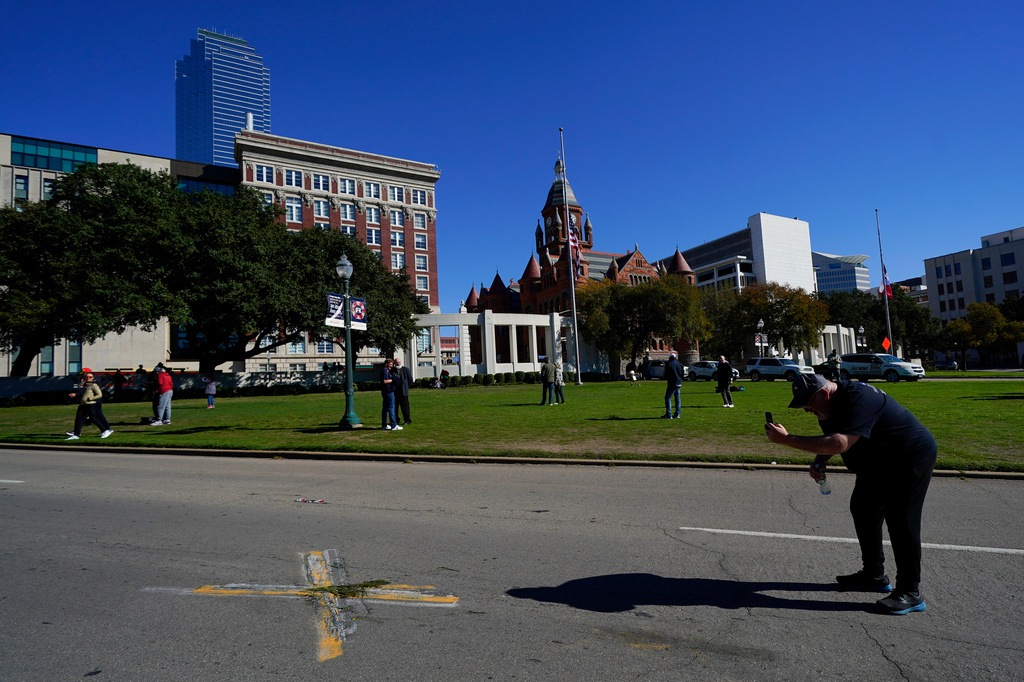 FILE - A person uses a cell phone to take pictures of an X on Elm Street at Dealey Plaza, one of two spots marked where President John F. Kennedy was shot, as people gather on the 60th anniversary of his assassination, Nov. 22, 2023, in Dallas. (AP Photo/Julio Cortez, File)