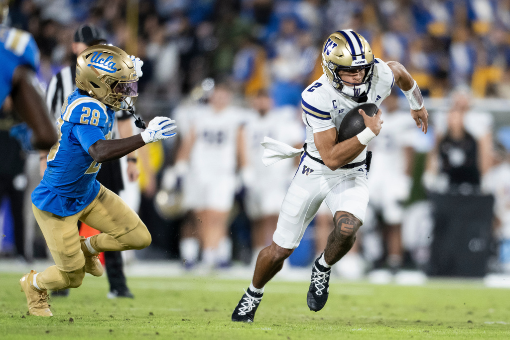 Washington quarterback Demond Williams Jr. runs with the ball past UCLA defensive back Scooter Jackson during the first half of an NCAA college football game, Saturday, Nov. 22, 2025, in Pasadena, Calif. (AP Photo/Kyusung Gong)