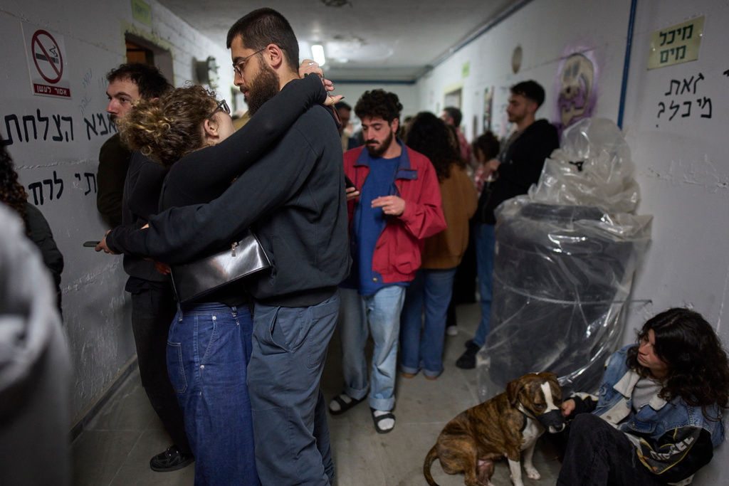People take shelter as air raid sirens signal a warning of incoming Iranian missiles in Tel Aviv, Israel, Monday, March 16, 2026. (AP Photo/Ohad Zwigenberg)