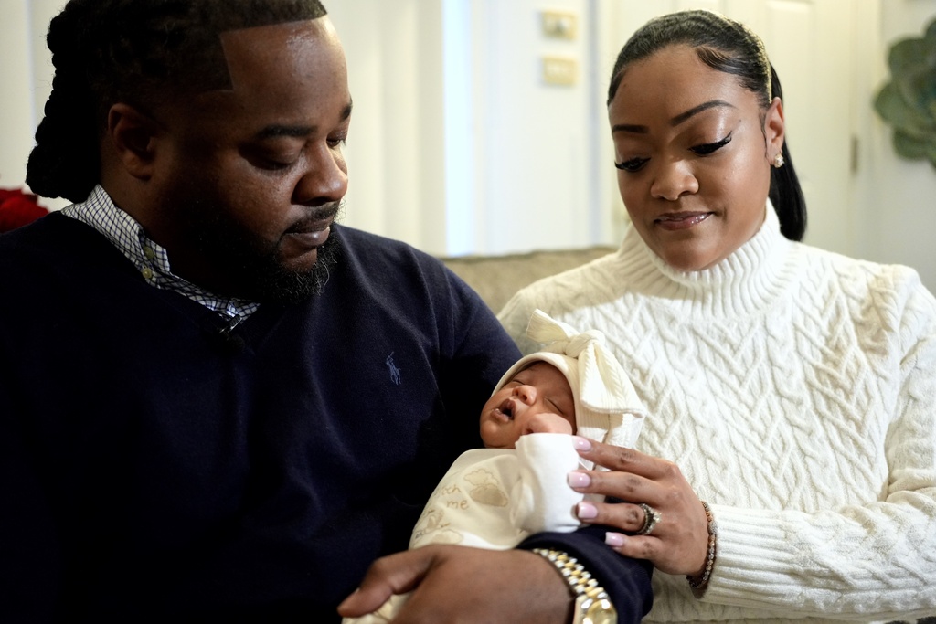 Leon and Mercedes Wells hold their newborn daughter Alena at their home in the Chicago suburb of Dolton, Ill. on Friday, Nov. 28, 2025. (AP Photo/Mark Vancleave)