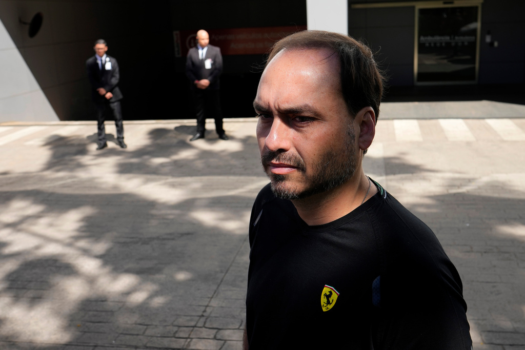 Carlos Bolsonaro, the son of former President Jair Bolsonaro, awaits his arrival in front of the hospital where he is being transported to from prison for surgery the next day, in Brasilia, Brazil, Wednesday, Dec. 24, 2025. (AP Photo/Eraldo Peres)