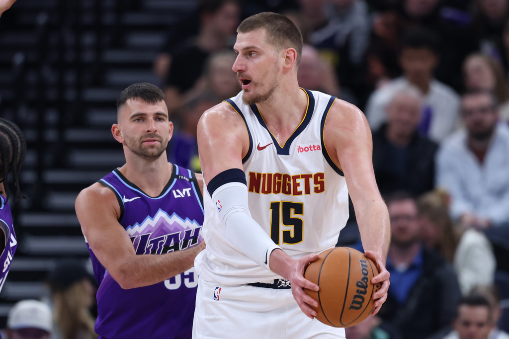 Denver Nuggets center Nikola Jokic (15) holds the ball away from Utah Jazz guard John Konchar during the first half of an NBA basketball game, Wednesday, April 1, 2026, in Salt Lake City. (AP Photo/Rob Gray)