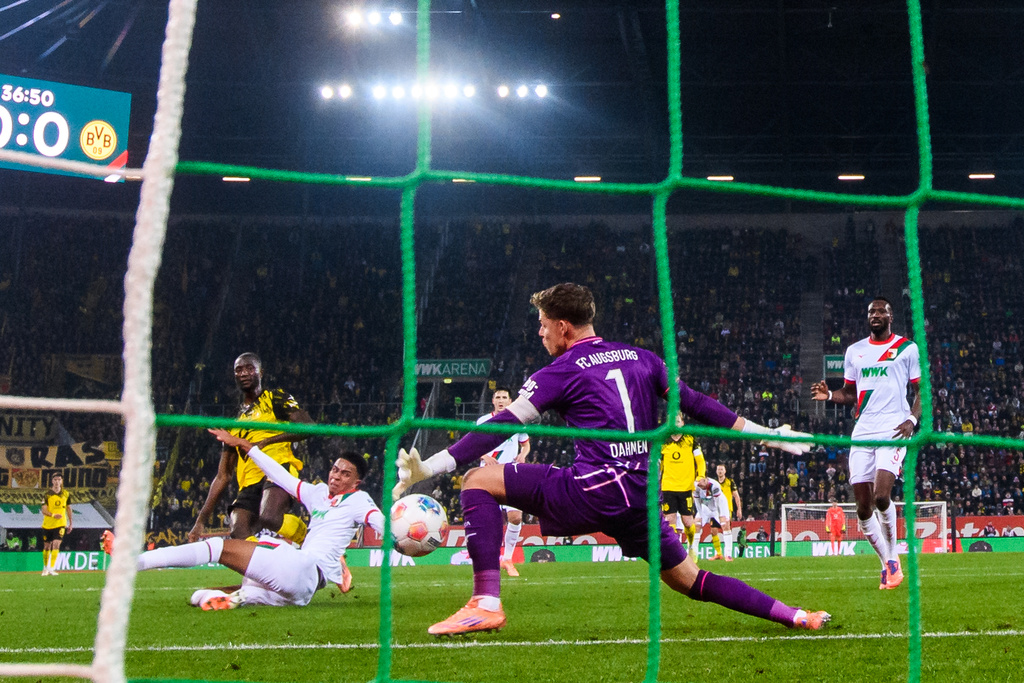 Dortmund's Serhou Guirassy , left, scores the goal past Augsburg's Noahkai Banks and goalkeeper Finn Dahmen during a Bundesliga soccer match between FC Augsburg and Borussia Dortmund, Friday, Oct. 31, 2025, in Augsburg, Germany. (Tom Weller/dpa via AP)