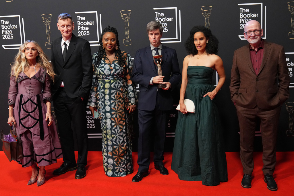 Hungarian-British author David Szalay, third right, stands with the judges after receiving the trophy for winning the Booker Prize 2025 for his book 'Flesh' at Old Billingsgate in London, Monday, Nov. 10, 2025. (AP Photo/Kirsty Wigglesworth)