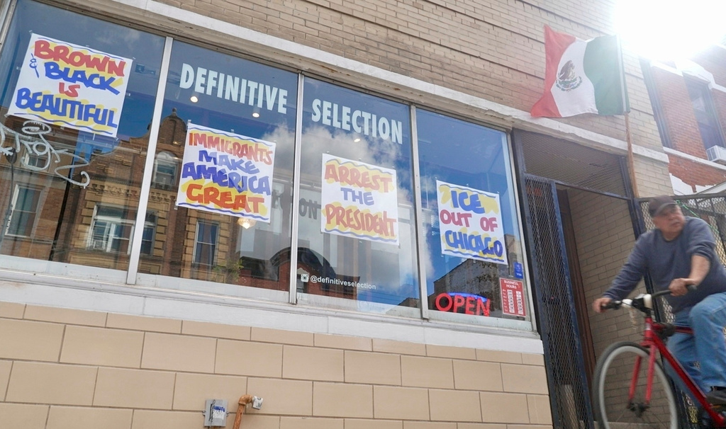 FILE - A bicyclist passes Definitive Selection clothing store, one of many businesses in the predominantly Latino neighborhood that has seen a slowdown in foot traffic since President Donald Trump's threats of a federal law enforcement intervention, Sept. 5, 2025, in Chicago. (AP Photo/Mark Vancleave, File)