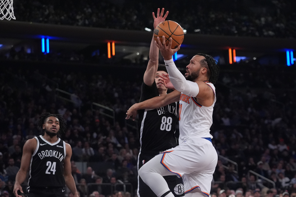 New York Knicks' Jalen Brunson, right, drives past Brooklyn Nets' Nolan Traore, center, as Cam Thomas, left, watches during the first half of an NBA basketball game Wednesday, Jan. 21, 2026, in New York. (AP Photo/Frank Franklin II)